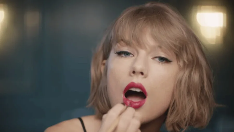 Η Taylor Swift βάφει τα χείλη της με κόκκινο κραγιόν σε κοντινό πλάνο.