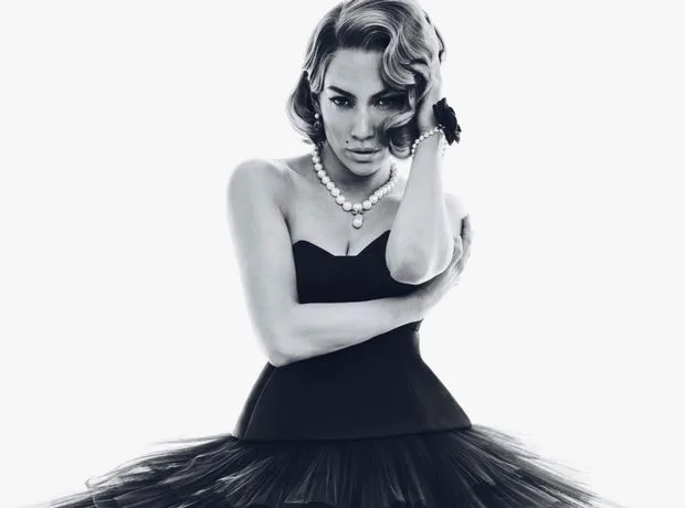 Η Jennifer Lopez σε ασπρόμαυρη καλλιτεχνική φωτογράφηση με μαύρο στράπλες φόρεμα και πέρλες.