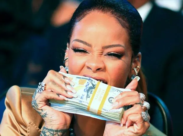 Η Rihanna δαγκώνει μια στοίβα χαρτονομίσματα των 100 δολαρίων.