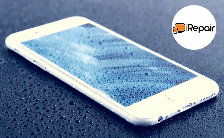 Ένα λευκό iPhone καλυμμένο με σταγόνες νερού πάνω σε βρεγμένη επιφάνεια με το λογότυπο της iRepair.