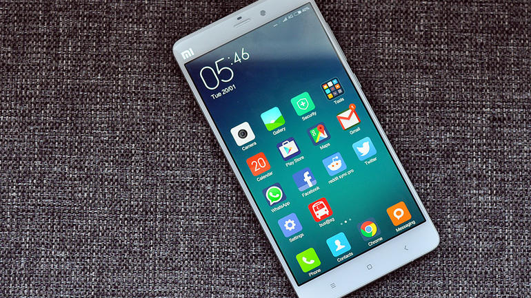 Λευκό smartphone Xiaomi Mi Note με αναμμένη οθόνη πάνω σε γκρι υφασμάτινη επιφάνεια.
