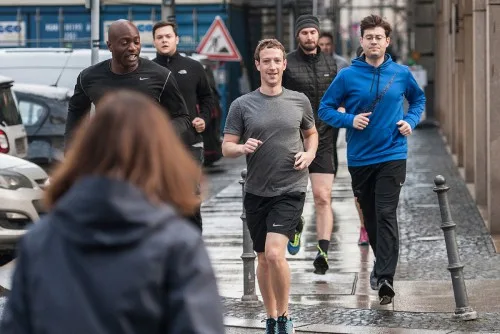 Ο Mark Zuckerberg τρέχει σε δρόμο της πόλης συνοδευόμενος από άνδρες της ασφάλειάς του.