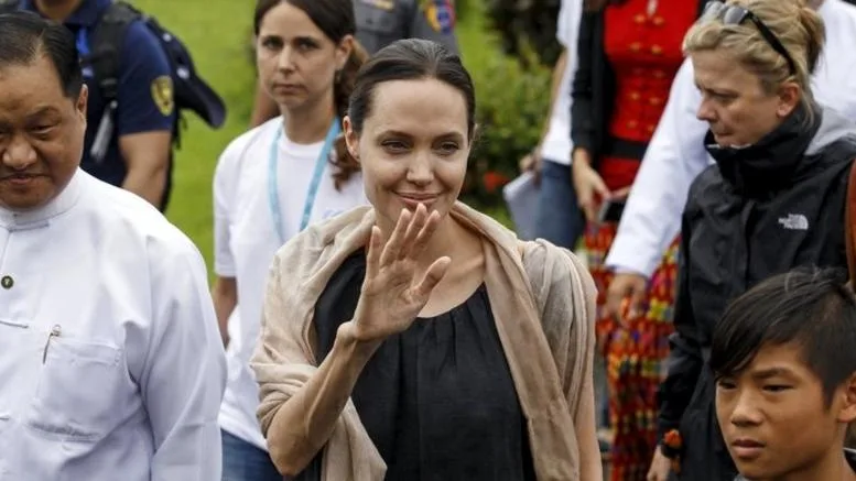 Η Angelina Jolie χαιρετά το πλήθος φορώντας μαύρο φόρεμα και εσάρπα.