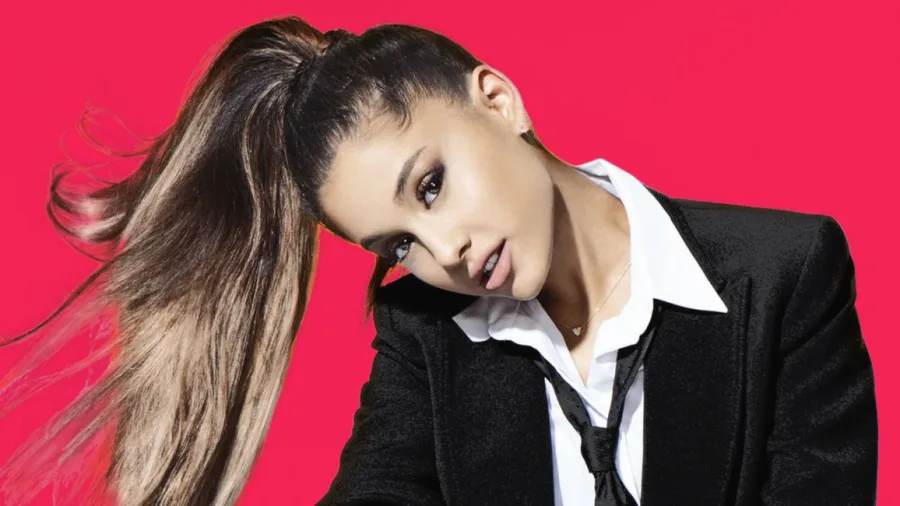 Η Ariana Grande με την χαρακτηριστική της αλογοουρά, φορώντας μαύρο σακάκι και λευκό πουκάμισο.