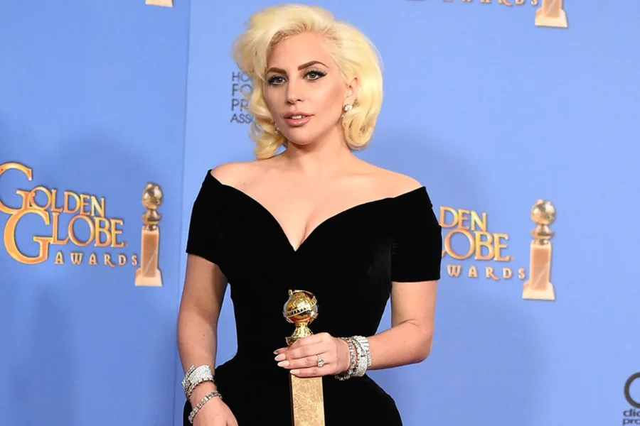Η Lady Gaga με μαύρο φόρεμα κρατώντας βραβείο Golden Globe.