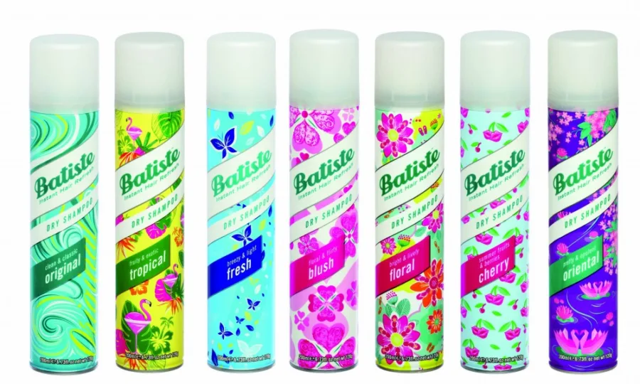 Σειρά από επτά πολύχρωμα μπουκάλια Batiste Dry Shampoo σε λευκό φόντο.