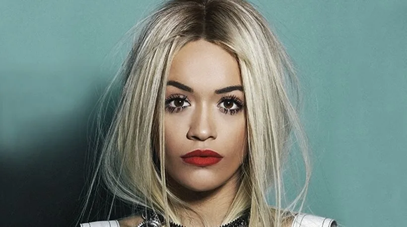 Κοντινό πορτρέτο της Rita Ora με ξανθά μαλλιά και κόκκινο κραγιόν.