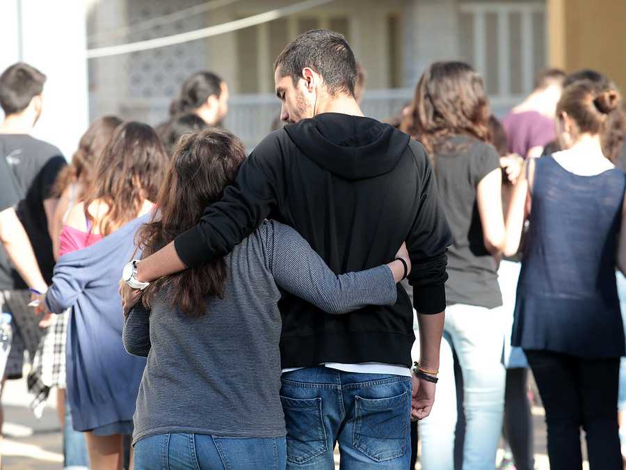Νεαροί μαθητές αγκαλιασμένοι σε εξωτερικό χώρο σχολείου.