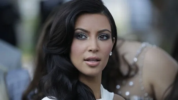 Η Kim Kardashian με μαύρα κυματιστά μαλλιά και λευκό ρούχο.