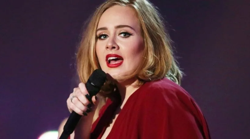 Η Adele τραγουδάει σε σκηνή κρατώντας μικρόφωνο
