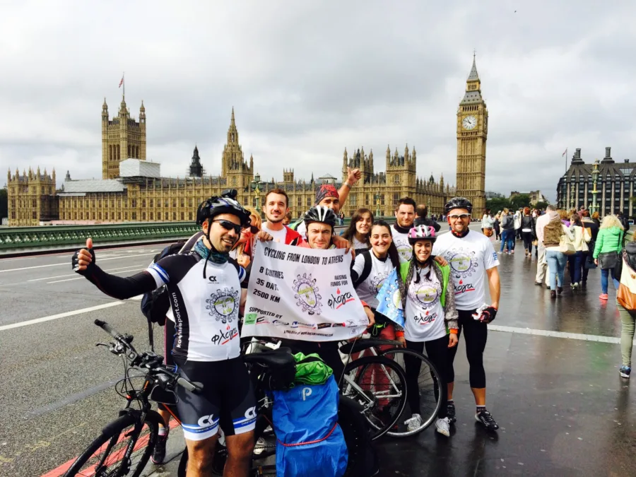 Ομάδα ποδηλατών με πανό Wheeling2help μπροστά από το Big Ben στο Λονδίνο.