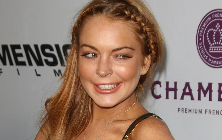 Η Lindsay Lohan σε εκδήλωση με πλεξούδα στα μαλλιά και χαμόγελο.