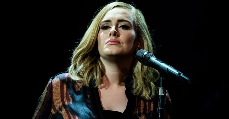 Η Adele τραγουδάει σε μικρόφωνο πάνω στη σκηνή.