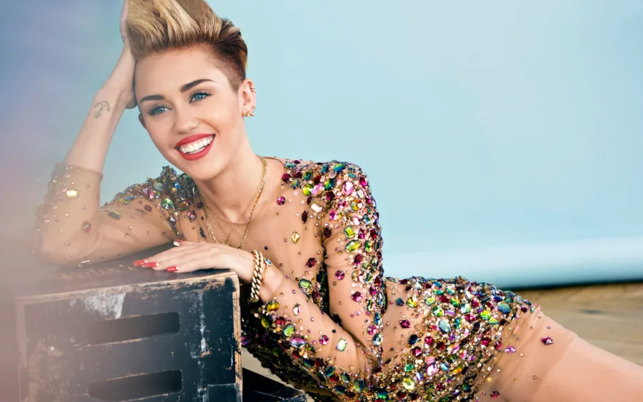 Η Miley Cyrus με κοντό ξανθό μαλλί και φόρεμα με πολύχρωμες πέτρες.
