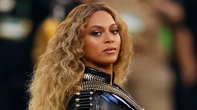 Η Beyonce με μακριά κυματιστά μαλλιά και μαύρο δερμάτινο ρούχο με χρυσές λεπτομέρειες.