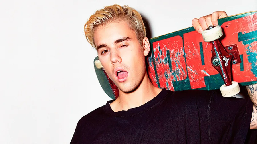 Ο Justin Bieber ποζάρει με ένα skateboard στον ώμο του.