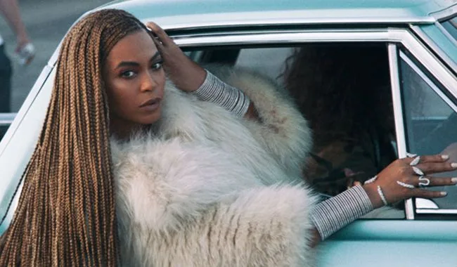 Η Beyonce με μακριές πλεξούδες και γούνα μέσα σε αυτοκίνητο.
