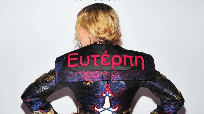 Η Madonna με πλάτη, φορώντας τζάκετ με την ελληνική λέξη Ευτέρπη κεντημένη με κόκκινα γράμματα.