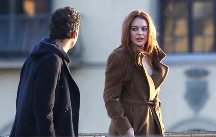 Η Lindsay Lohan με καφέ παλτό στη Φλωρεντία δίπλα σε έναν άνδρα.