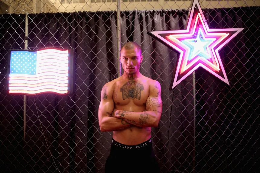 Ο Jeremy Meeks ποζάρει μπροστά από συρματόπλεγμα με νέον διακοσμητικά.