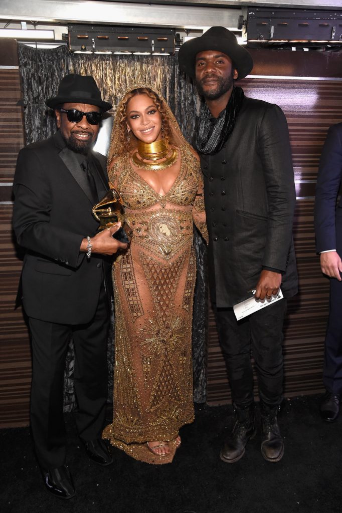 Η Beyoncé με χρυσό φόρεμα στα βραβεία Grammy μαζί με δύο άνδρες.