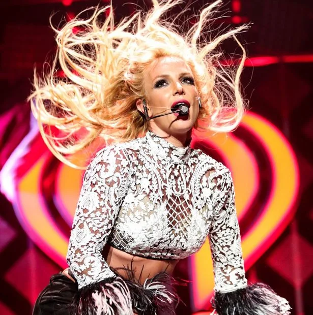 Η Britney Spears στη σκηνή με λευκό δαντελωτό τοπ και μικρόφωνο κεφαλής.