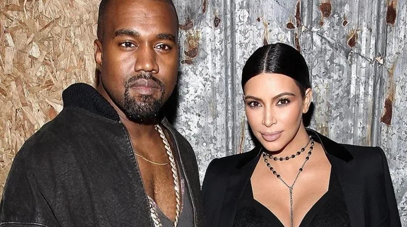 Ο Kanye West και η Kim Kardashian ποζάρουν μαζί μπροστά από μεταλλικό φόντο.