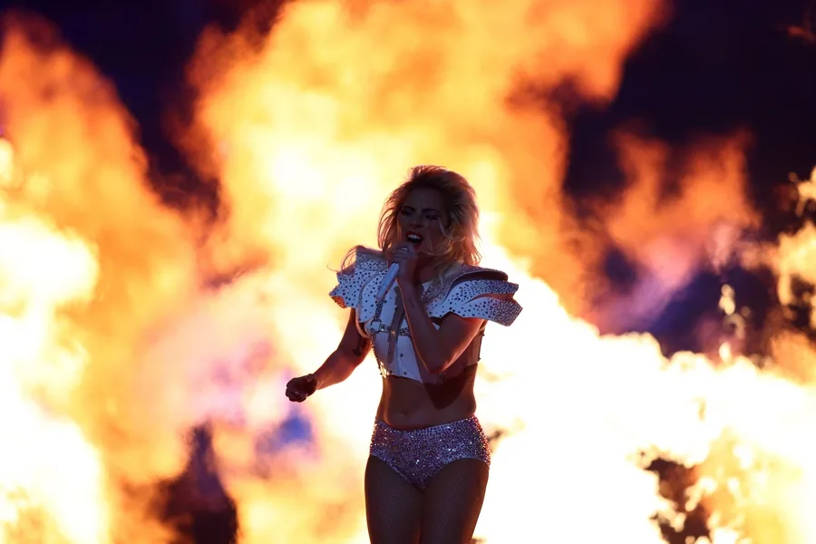Η Lady Gaga τραγουδάει στη σκηνή του Super Bowl με φόντο φλόγες.
