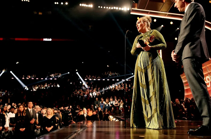 Η Adele στη σκηνή των βραβείων Grammy κρατώντας ένα βραβείο.