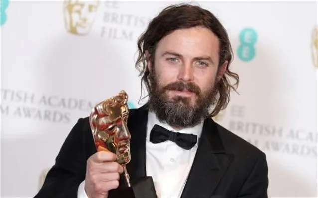 Άνδρας ηθοποιός με μούσι κρατάει βραβείο BAFTA.