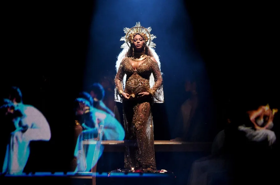 Η Beyoncé στη σκηνή των βραβείων Grammy με χρυσό φόρεμα και στέμμα.