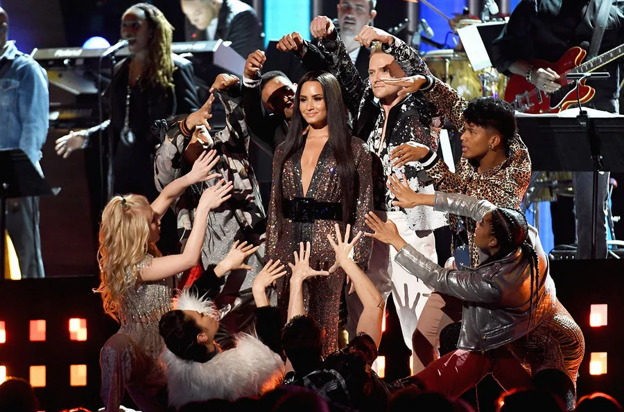 Τραγουδίστρια στη σκηνή των Grammys περιτριγυρισμένη από χορευτές.