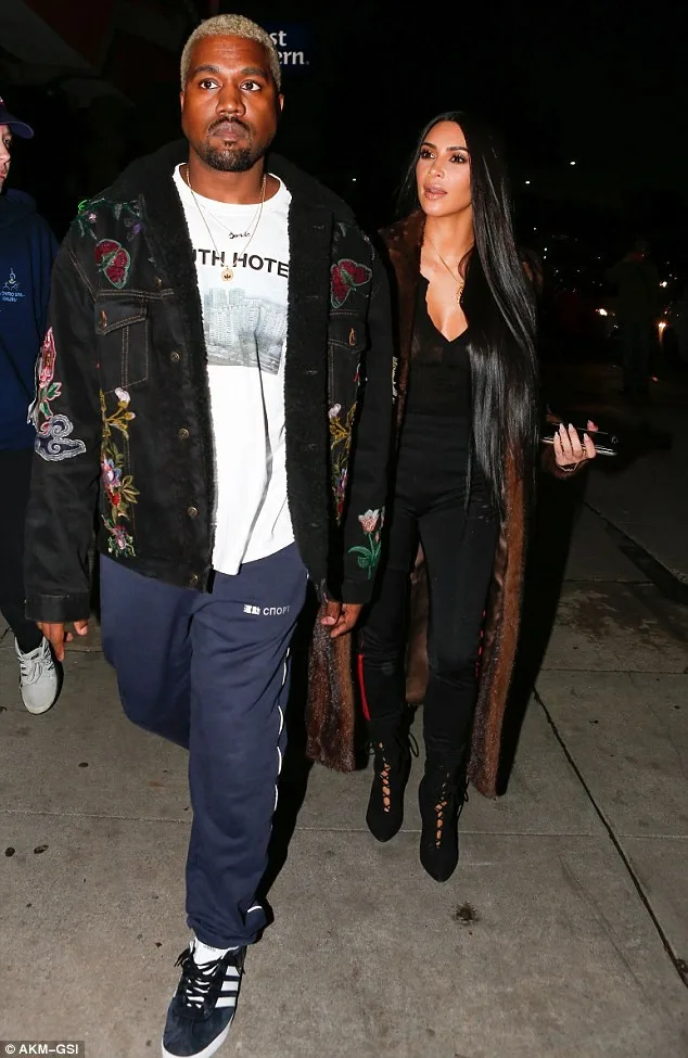 Ο Kanye West και η Kim Kardashian περπατούν στο δρόμο το βράδυ.