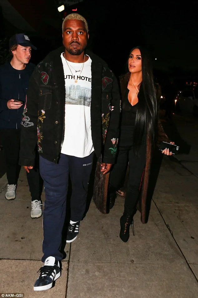 Ο Kanye West και η Kim Kardashian περπατούν στο δρόμο το βράδυ.
