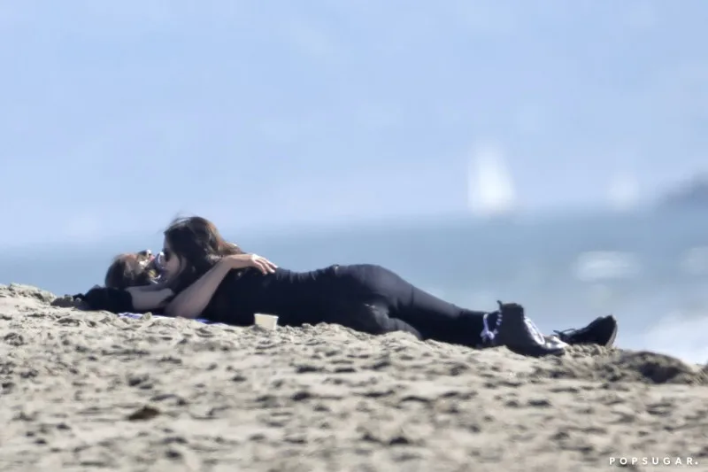 Ο Bradley Cooper και η Irina Shayk ξαπλωμένοι στην άμμο σε παραλία.