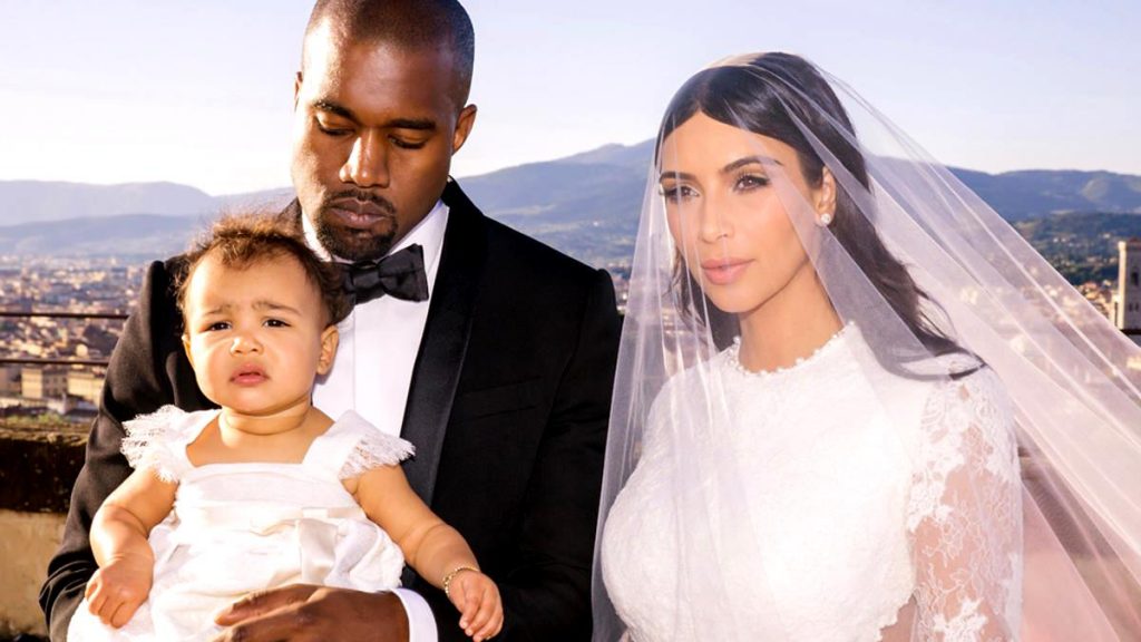 Η Kim Kardashian με νυφικό, ο Kanye West με σμόκιν και η κόρη τους North West σε γαμήλια φωτογραφία.