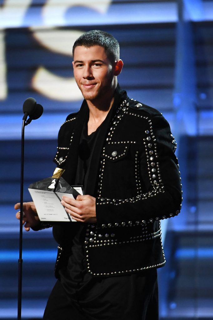 Καλλιτέχνης στη σκηνή των βραβείων Grammys κρατώντας έναν φάκελο.