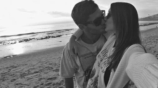 Ένα ζευγάρι φιλιέται στην παραλία σε ασπρόμαυρη φωτογραφία.