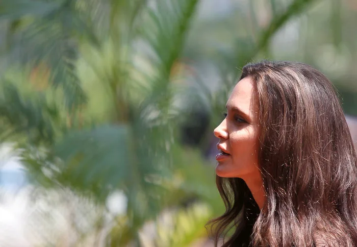 Προφίλ της Angelina Jolie με φόντο φοίνικες.