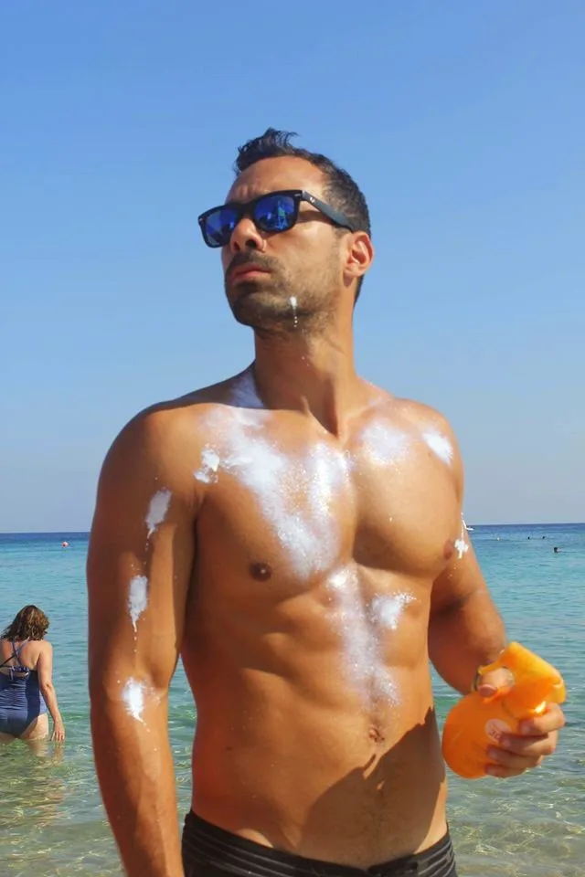 Ο Σάκης Τανιμανίδης στην παραλία με αντηλιακό.