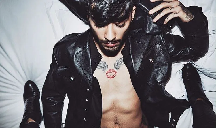 Ο Zayn Malik ξαπλωμένος με ανοιχτό δερμάτινο τζάκετ.