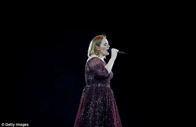 Η Adele τραγουδάει σε σκηνή με μικρόφωνο