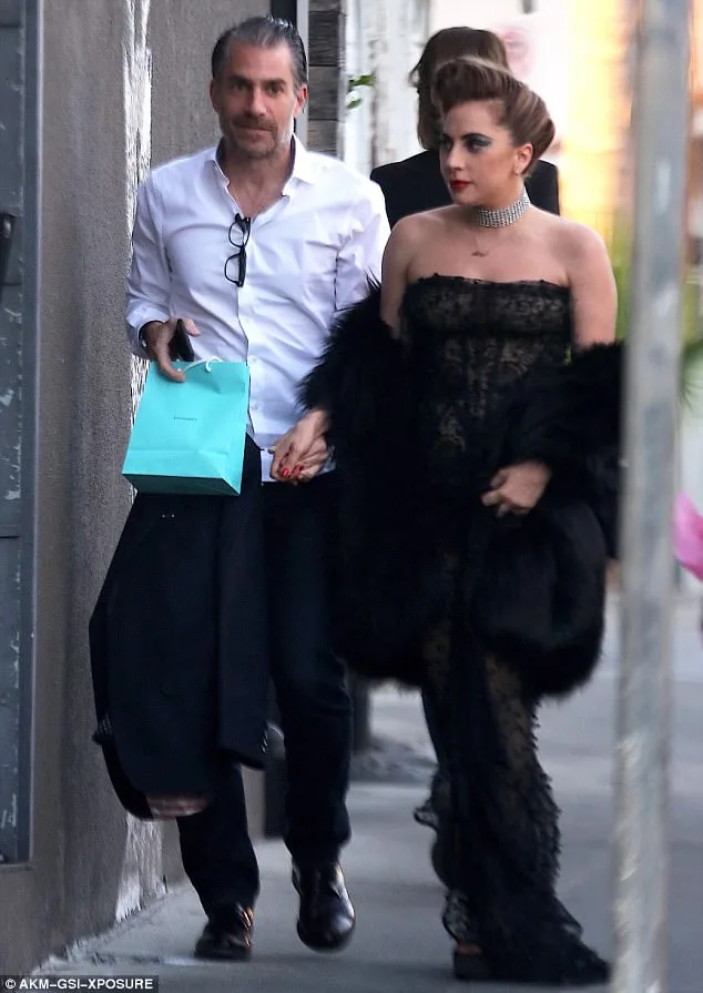 Η Lady Gaga και ο Christian Carino περπατούν στο δρόμο πιασμένοι χέρι-χέρι.