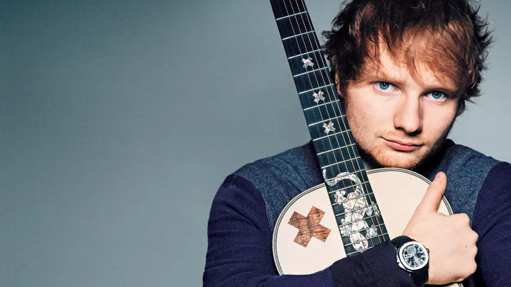 Ο Ed Sheeran κρατάει μια ακουστική κιθάρα.