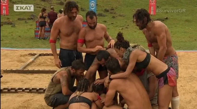 Παίκτες του Survivor αγκαλιασμένοι σε κύκλο στην άμμο.