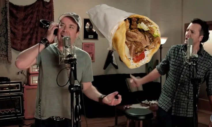 Ο Jimmy Fallon και ο Luke Bryan τραγουδούν σε στούντιο με έναν ιπτάμενο ελληνικό γύρο ανάμεσά τους.