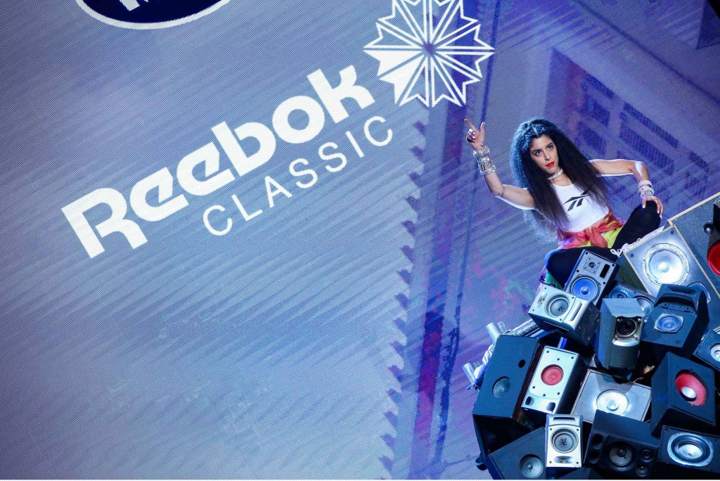 Καλλιτέχνης στη σκηνή του MadWalk 2017 μπροστά από το λογότυπο Reebok Classic.