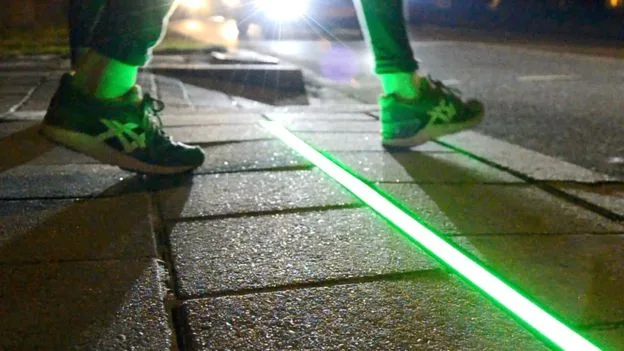 Φωτιζόμενη πράσινη λωρίδα LED στο πεζοδρόμιο μιας διάβασης πεζών τη νύχτα.