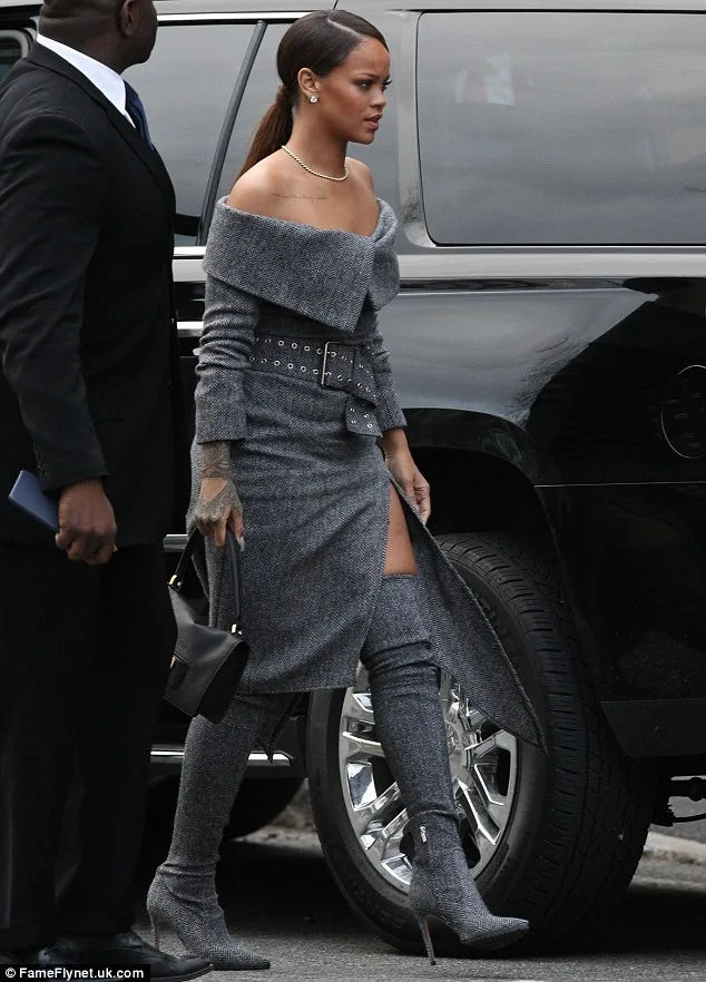 Η Rihanna με γκρι tweed φόρεμα και ασορτί μπότες δίπλα σε ένα μαύρο όχημα.