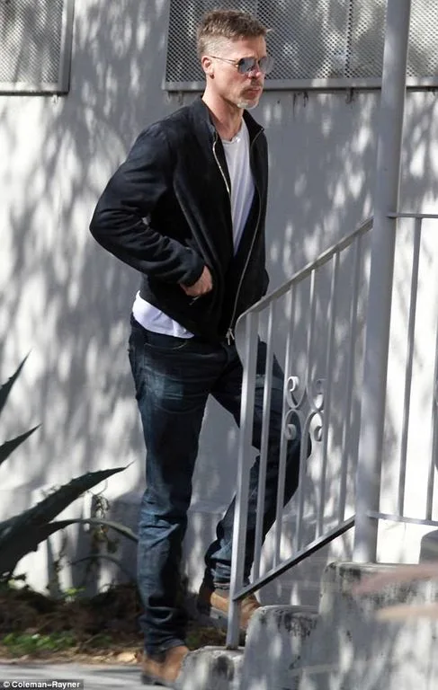 Ο Brad Pitt με μαύρο τζάκετ και γυαλιά ηλίου ανεβαίνει σκαλιά.
